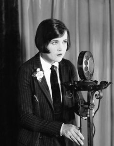 A woman from the 1940's stands at a large microphone