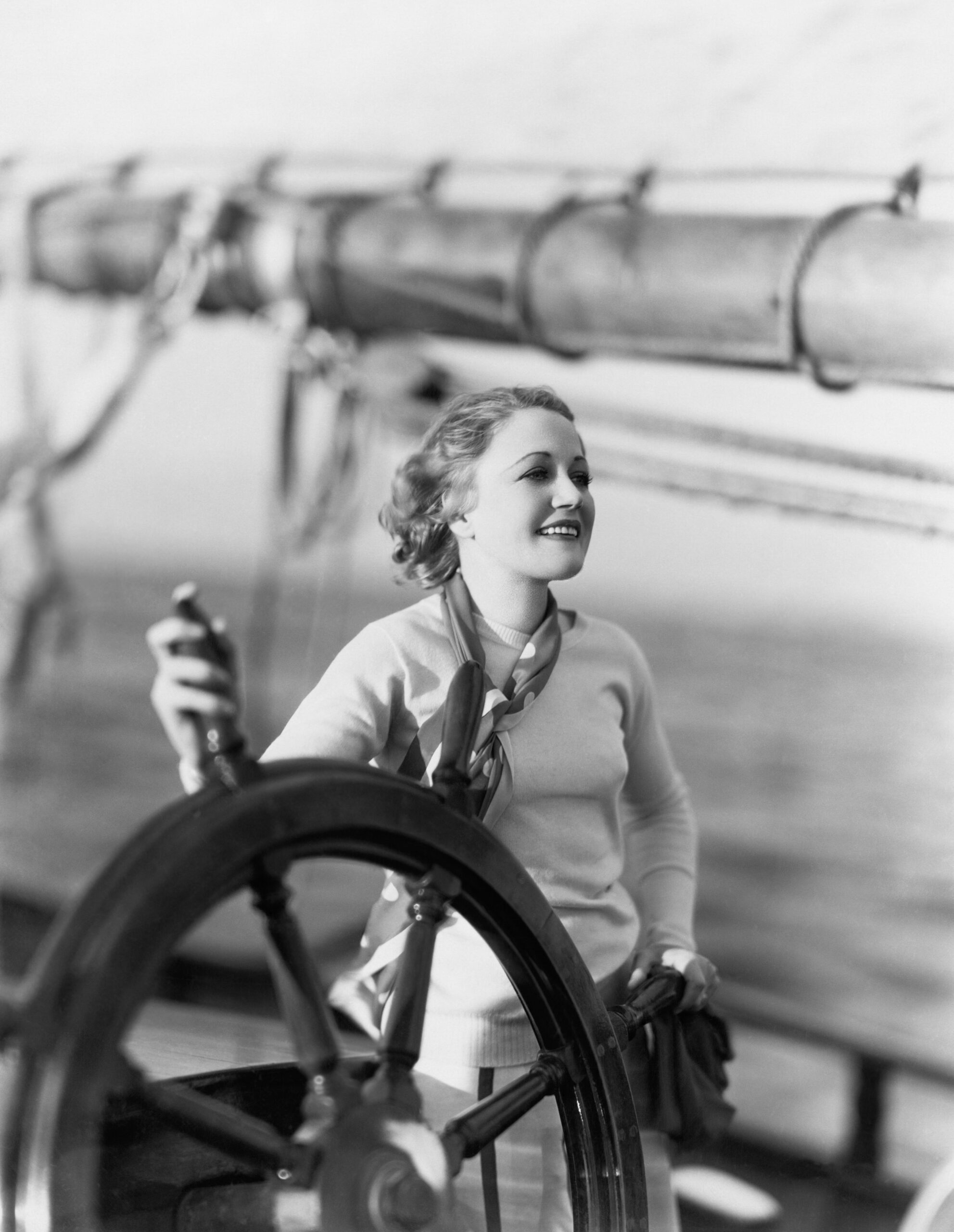Young women faces into the wind holding the steering wheel of a ship